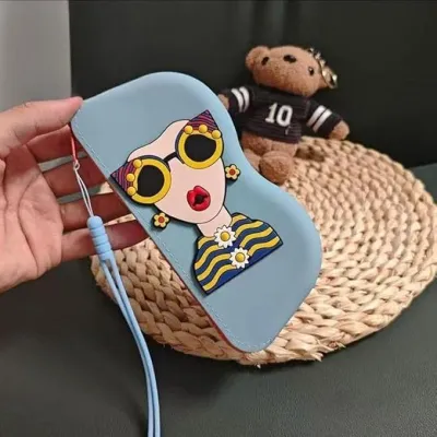 A light blue Cartoon Sunglasses Case held over a woven mat next to a small plush teddy bear accessory.
