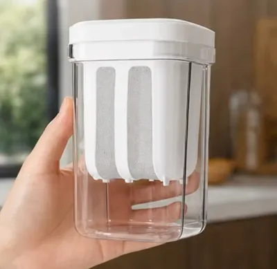 A hand holding the compact clear container of a Greek Yogurt Strainer showing its size and mesh insert.