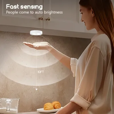 Woman reaching under a kitchen cabinet towards a mounted rechargeable round motion sensor light with motion range.