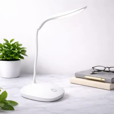 Unlit white rechargeable study lamp price in Pakistan placed on a marble surface next to glasses and books.