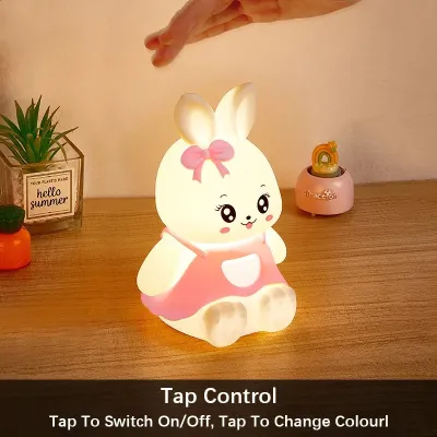 Blue Silicone Bunny Night Light illuminated in warm white mode on a wooden bedside table.